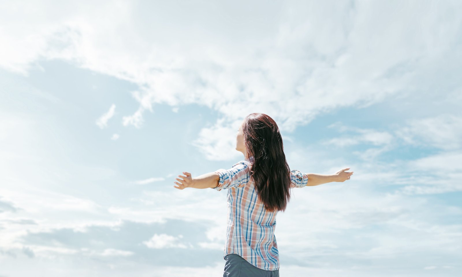 Woman standing with arms outstretched looking toward the sky